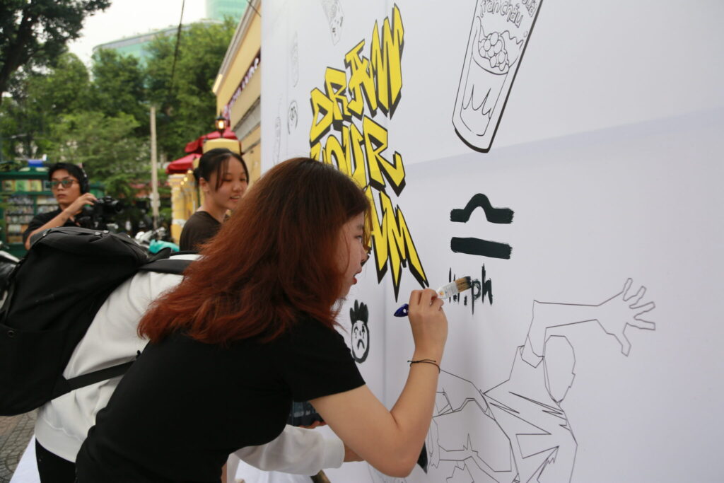 Young participants showing off their creativity on the “Draw Your Dream” community mural